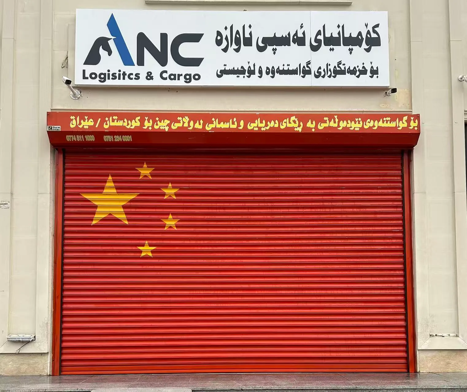 ANC 埃尔比勒办公室入口，红色卷帘门上方悬挂公司招牌